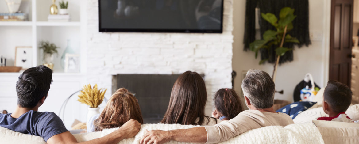 Back view of three generation Hispanic family sitting on the sofa watching TV