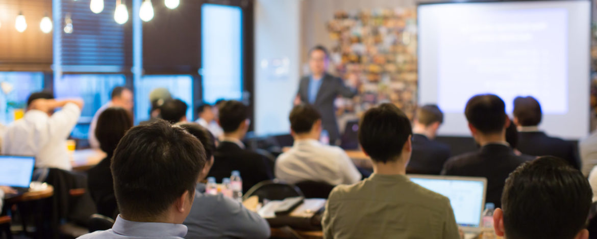 Audience Listens to Lecturer at a Conference Meeting Seminar Training. Group of People Hear Presenter Give Speech . Corporate Manager Speaker Gives Business Technology and Economic Forecast.