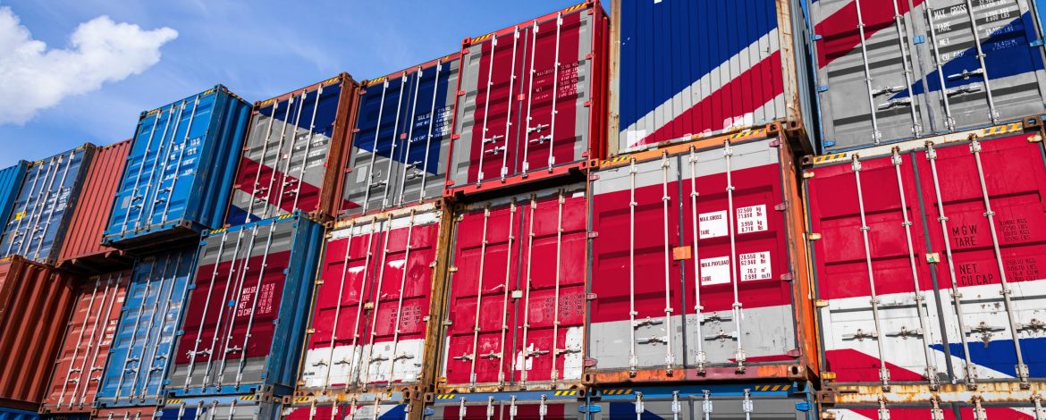 The national flag of United Kingdom on a large number of metal containers for storing goods stacked in rows on top of each other. Conception of storage of goods by importers, exporters